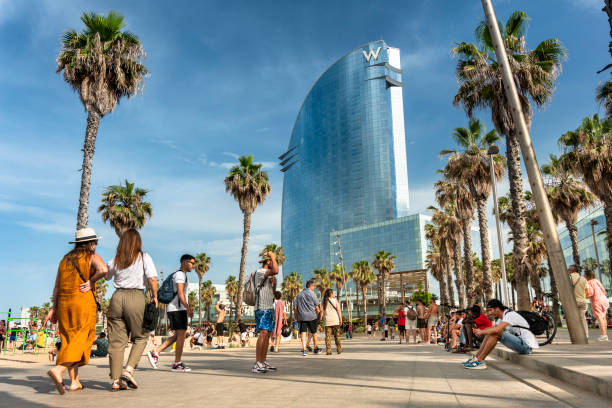 una multitud de personas caminan por el paseo marítimo de la playa de la barceloneta en barcelona españa - barceloneta barcelona fotografías e imágenes de stock